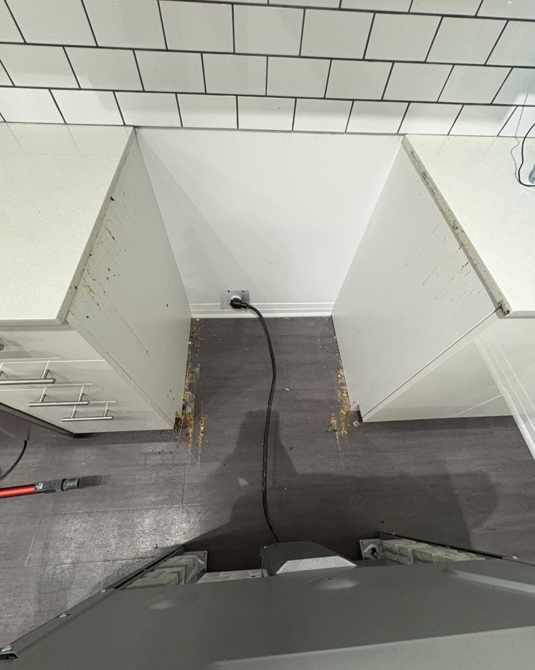 Under-range floor grime and cabinet buildup before clean