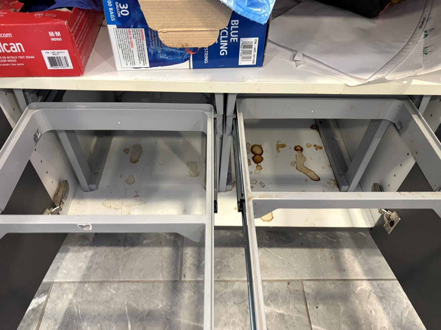 Spills and stains inside lower cabinet base before cleaning
